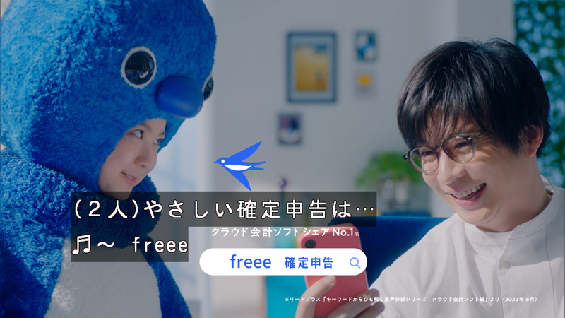新キャラクターふーちゃんと俳優田中圭さんが一緒にスマートフォンを見ながら談笑している。字幕入りの画像。